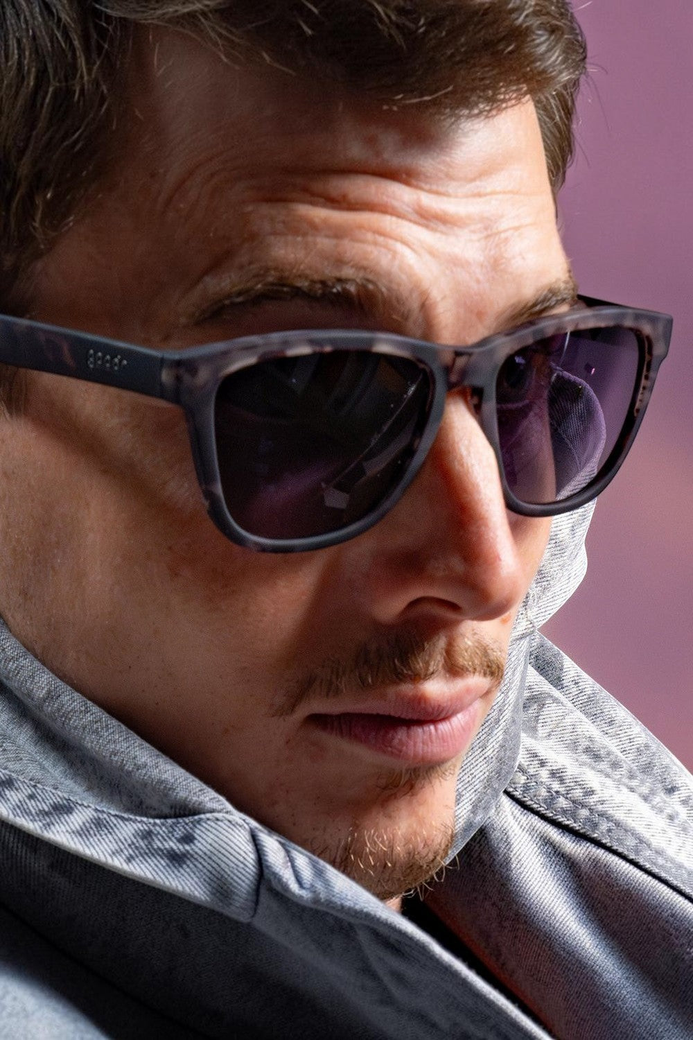 Homem usando óculos de sol SPORTBR Goodr cinza com lentes pretas polarizadas em close-up lateral.