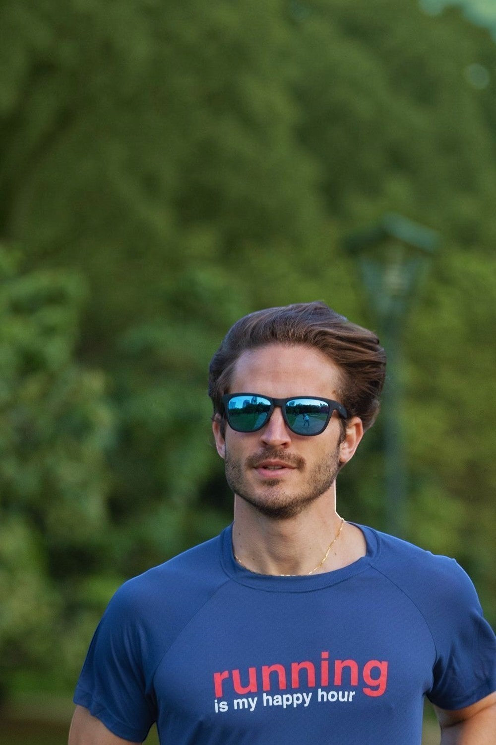 Homem correndo ao ar livre usando óculos de sol SPORTBR Goodr com armação preta e lentes espelhadas azuis polarizadas.