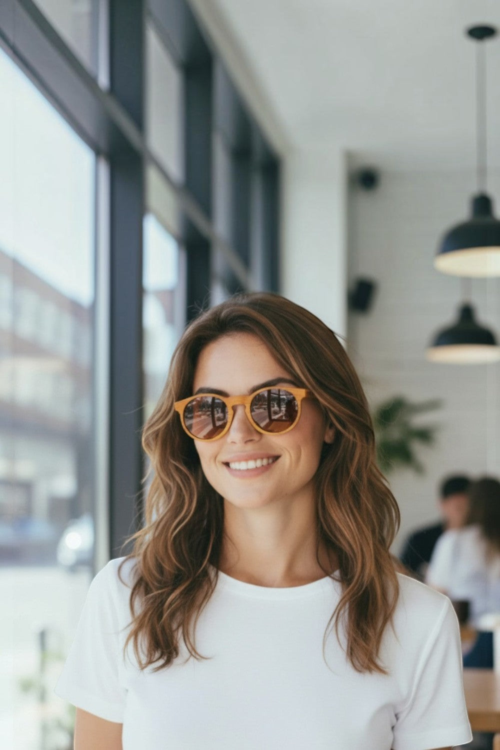 Mulher sorridente usando óculos de sol SPORTBR Goodr Bodhi’s Ultimate Ride com armação e lentes marrons redondas.