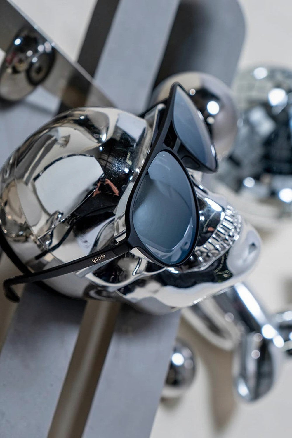 Óculos de sol SPORTBR Goodr Add the Chrome Package com armação preta e lentes espelhadas cinza em suporte cromado