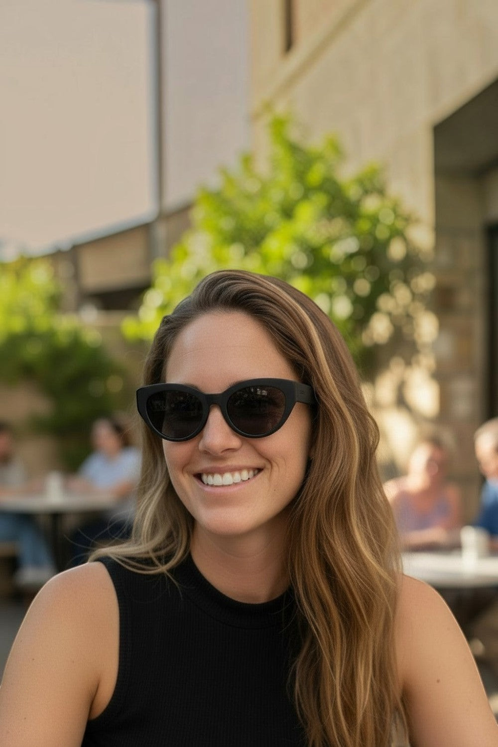 Mulher sorrindo usando óculos de sol pretos SPORTBR Goodr In My Cosmic Era com lentes polarizadas em ambiente externo.