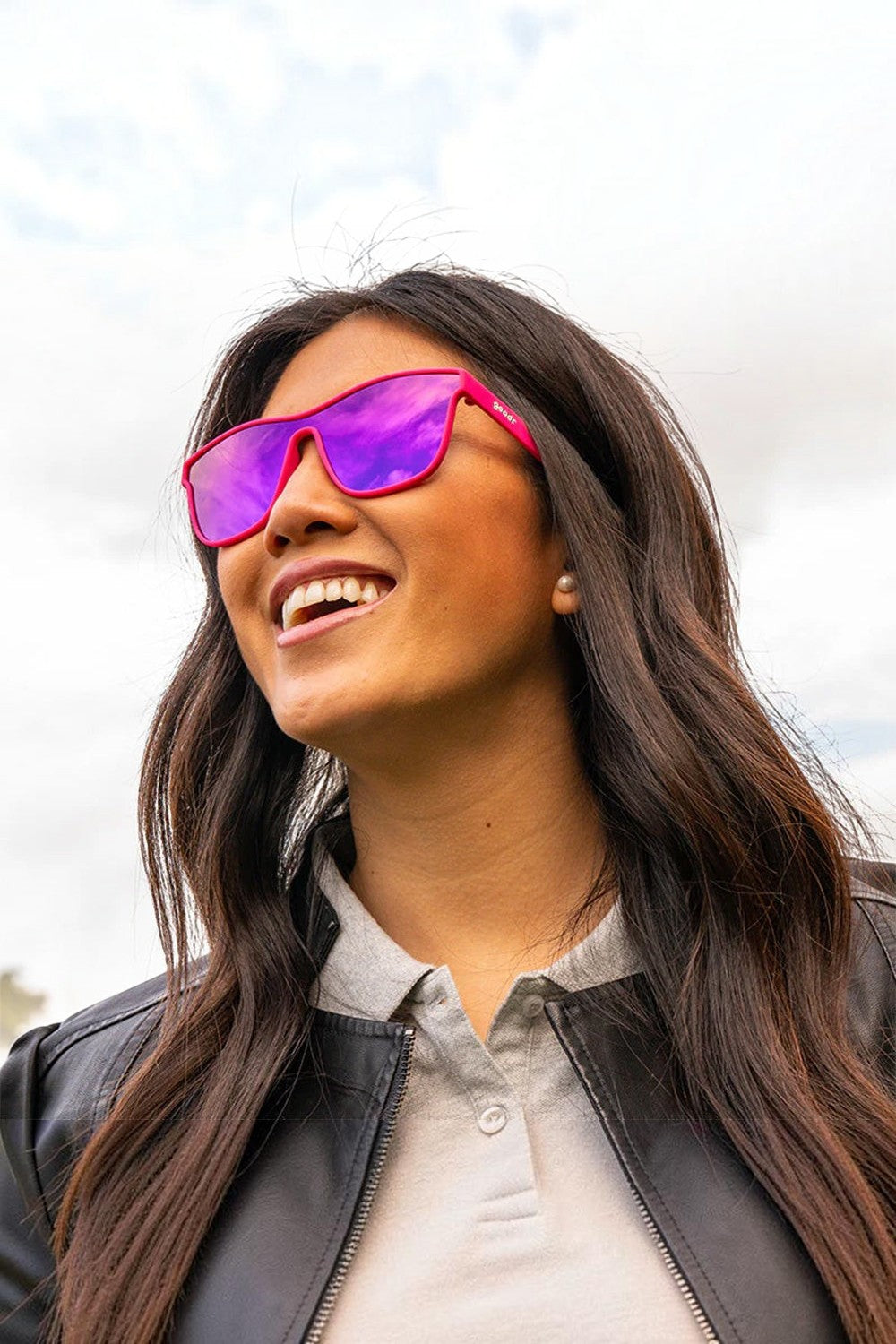 Mulher usando óculos de sol SPORTBR Goodr rosa com lentes espelhadas roxas, ideal para corrida e esportes ao ar livre.