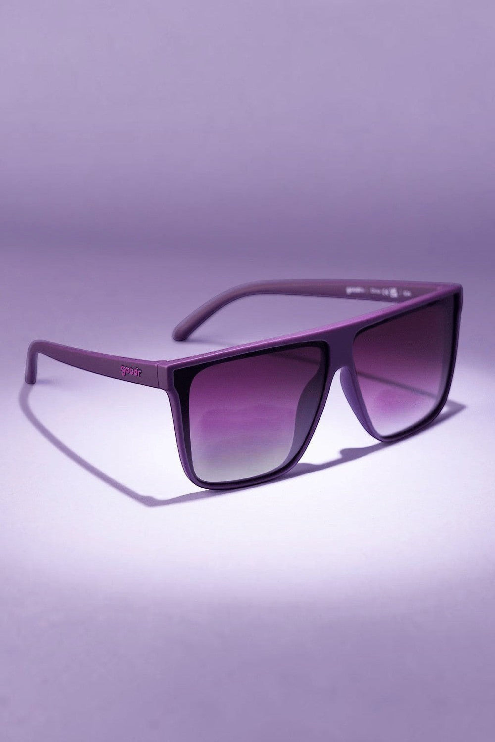 Óculos de sol SPORTBR Goodr Keeping a High Profile roxo com lentes polarizadas para corrida em fundo lilás.