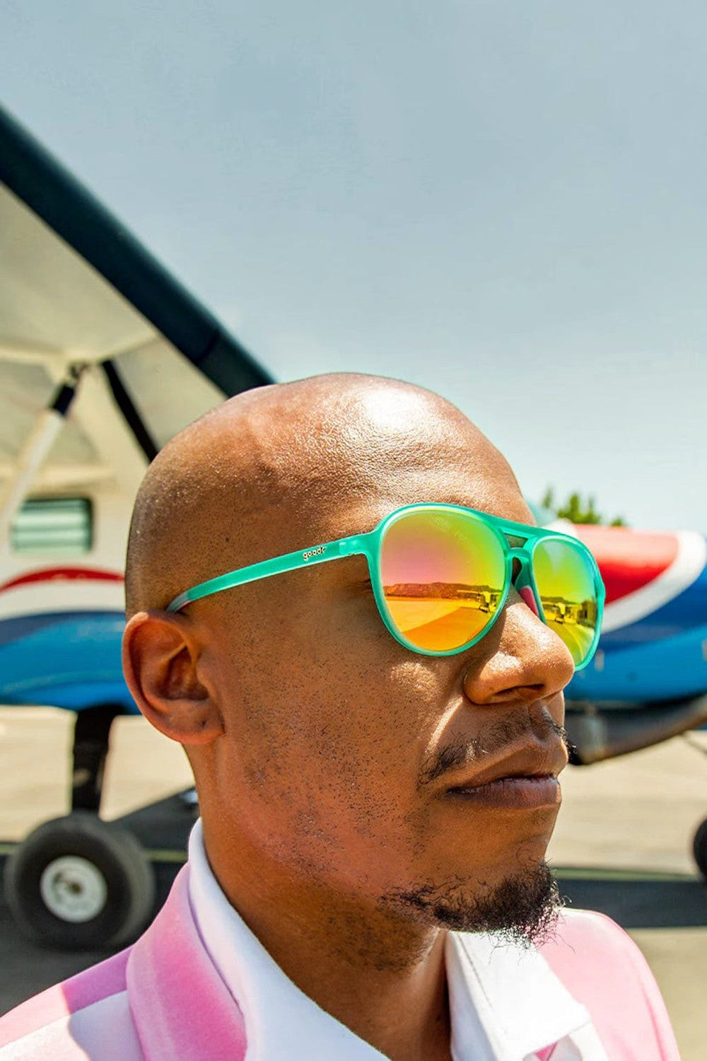 Homem usando óculos de sol SPORTBR Goodr Kitty Hawkers verdes com lentes espelhadas amarelas polarizadas.