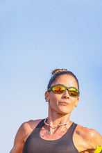 Mulher usando óculos de sol esportivos verdes Goodr com lentes âmbar espelhadas durante corrida ao ar livre