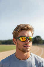 Homem usando óculos de sol SPORTBR Goodr Grass Stain Hall of Fame com armação verde e lentes espelhadas âmbar na pista