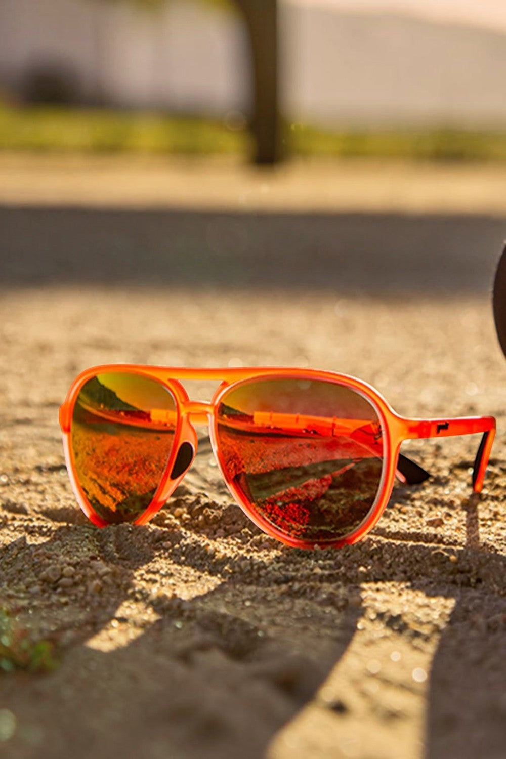 Óculos de sol SPORTBR Goodr Captain Blunt's Red-Eye com armação vermelha e lentes espelhadas rosas em ambiente externo.