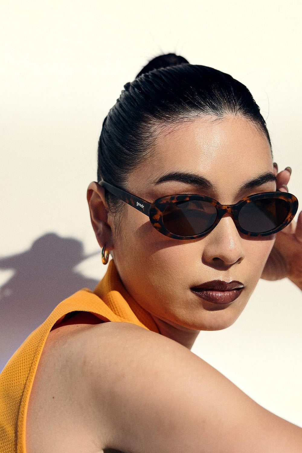 Mulher usando óculos de sol SPORTBR Goodr Karaoke Machine Solo com armação tartaruga e lentes marrons polarizadas