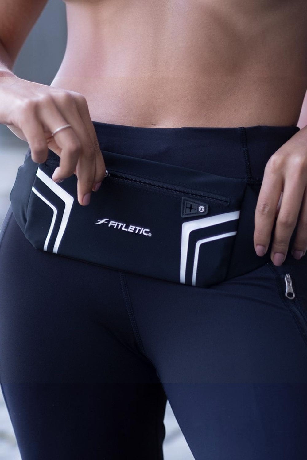 Pochete esportiva preta SPORTBR Fitletic Blitz com painel refletivo e zíper, usada na cintura para corrida.