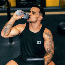 SPORTBR homem bebendo água de uma garrafa em uma academia, usando regata preta com logo Z2.