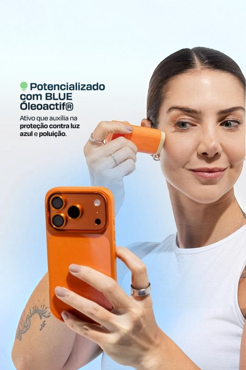 Mulher aplicando protetor solar em bastão SPORTBR Pink Cheeks no rosto, com celular laranja na mão.