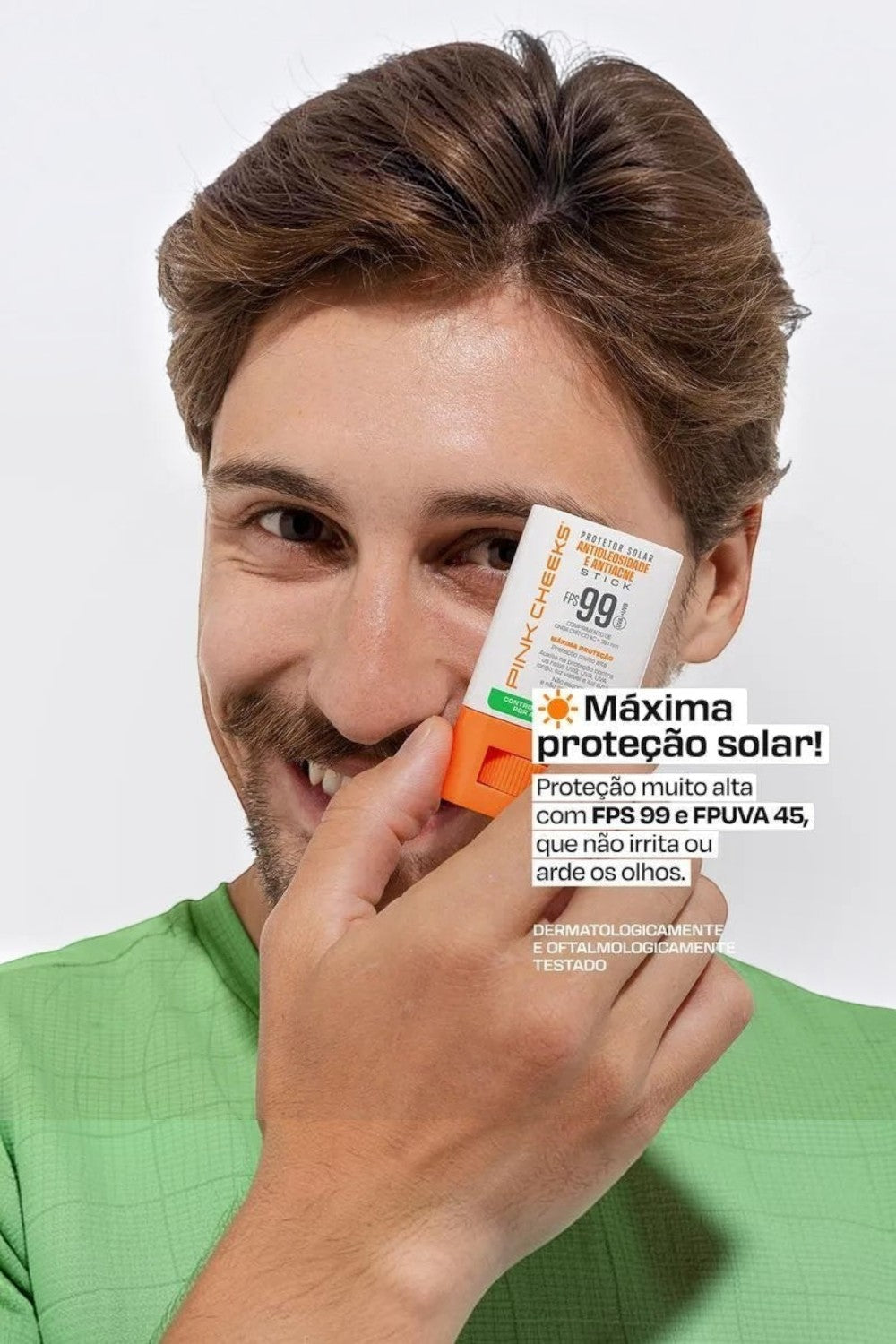 Homem sorridente segurando protetor solar em bastão Pink Cheeks SPORTBR com FPS 99 e acabamento matte no rosto.