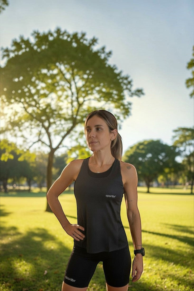 Corredora usando regata preta SPORTBR AirMesh em parque ensolarado, focada em performance e respirabilidade.