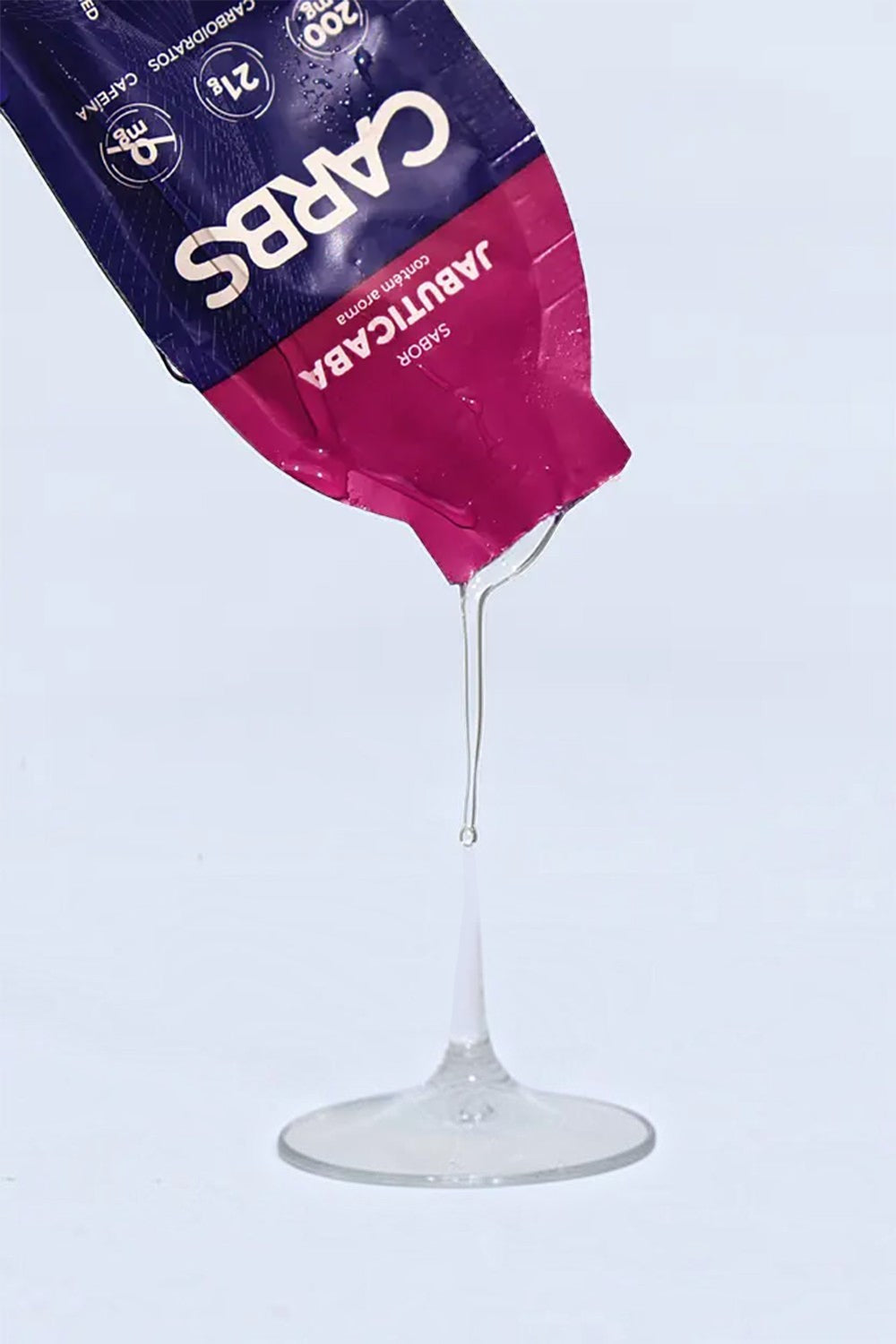 Sachê de gel de carboidrato SPORTBR sabor jabuticaba com textura líquida e transparente sendo despejado.