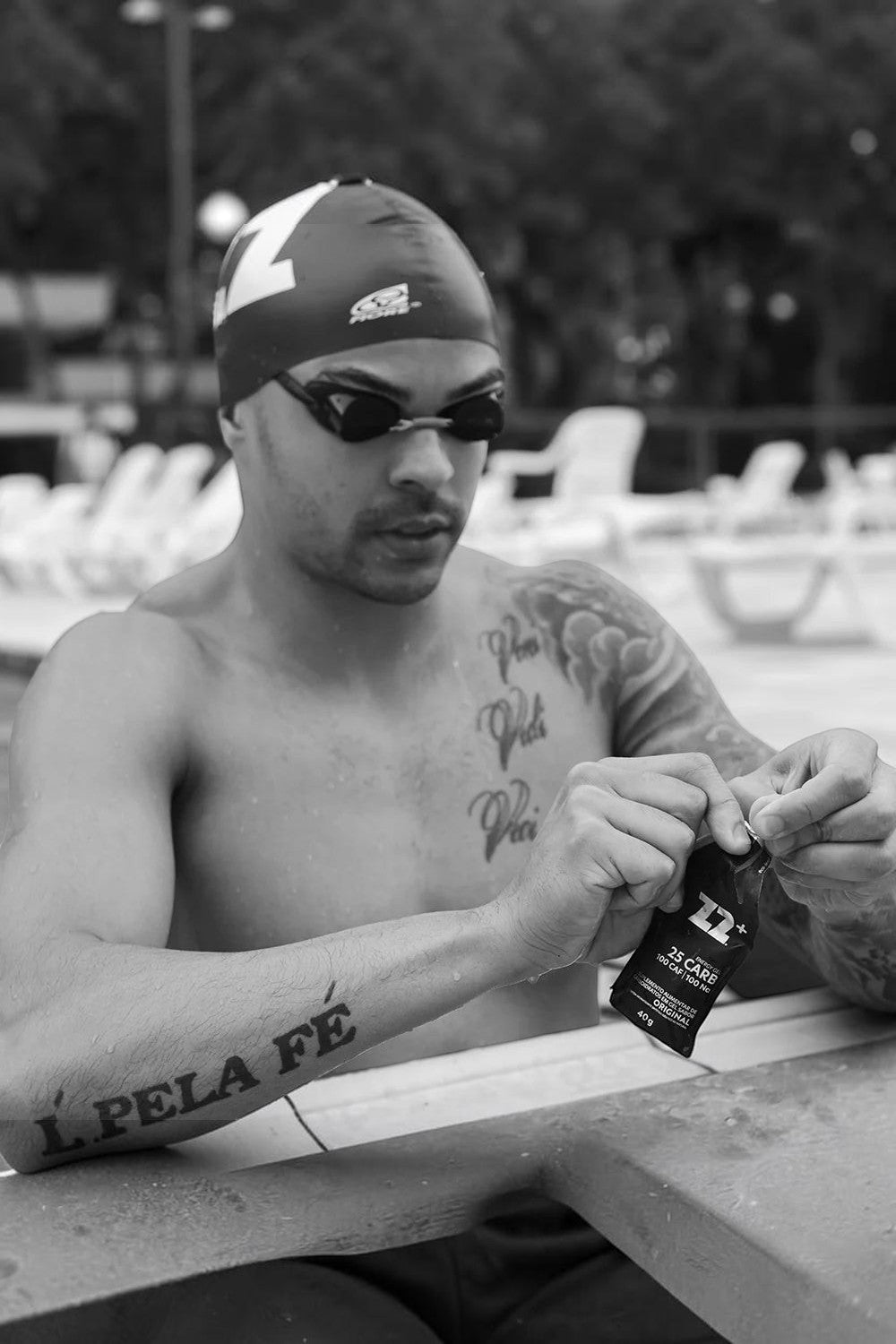 Atleta SPORTBR abrindo sachê de gel de carboidrato Z2+ 40g na borda da piscina para treino de natação