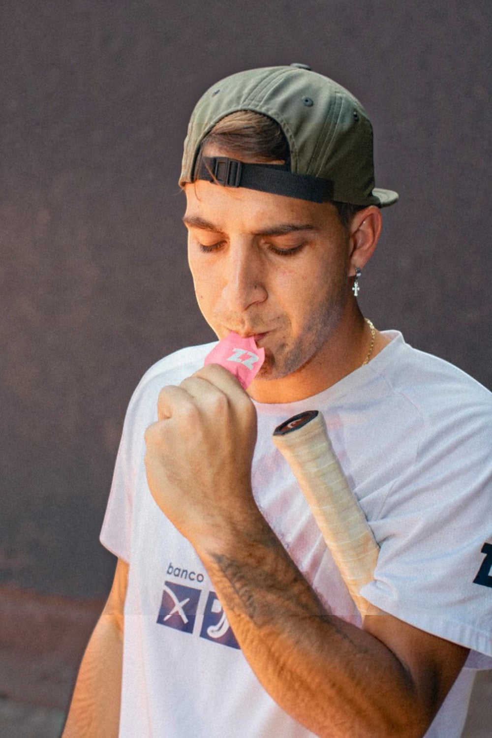 Homem usando boné verde consumindo sachê de gel de carboidrato Z2 sabor Pink Lemonade da SPORTBR durante treino