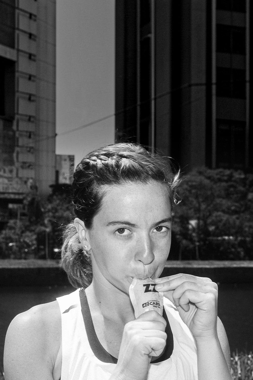 Mulher atleta consumindo sachê de gel de carboidrato SPORTBR Z2+ 40g durante treino ao ar livre
