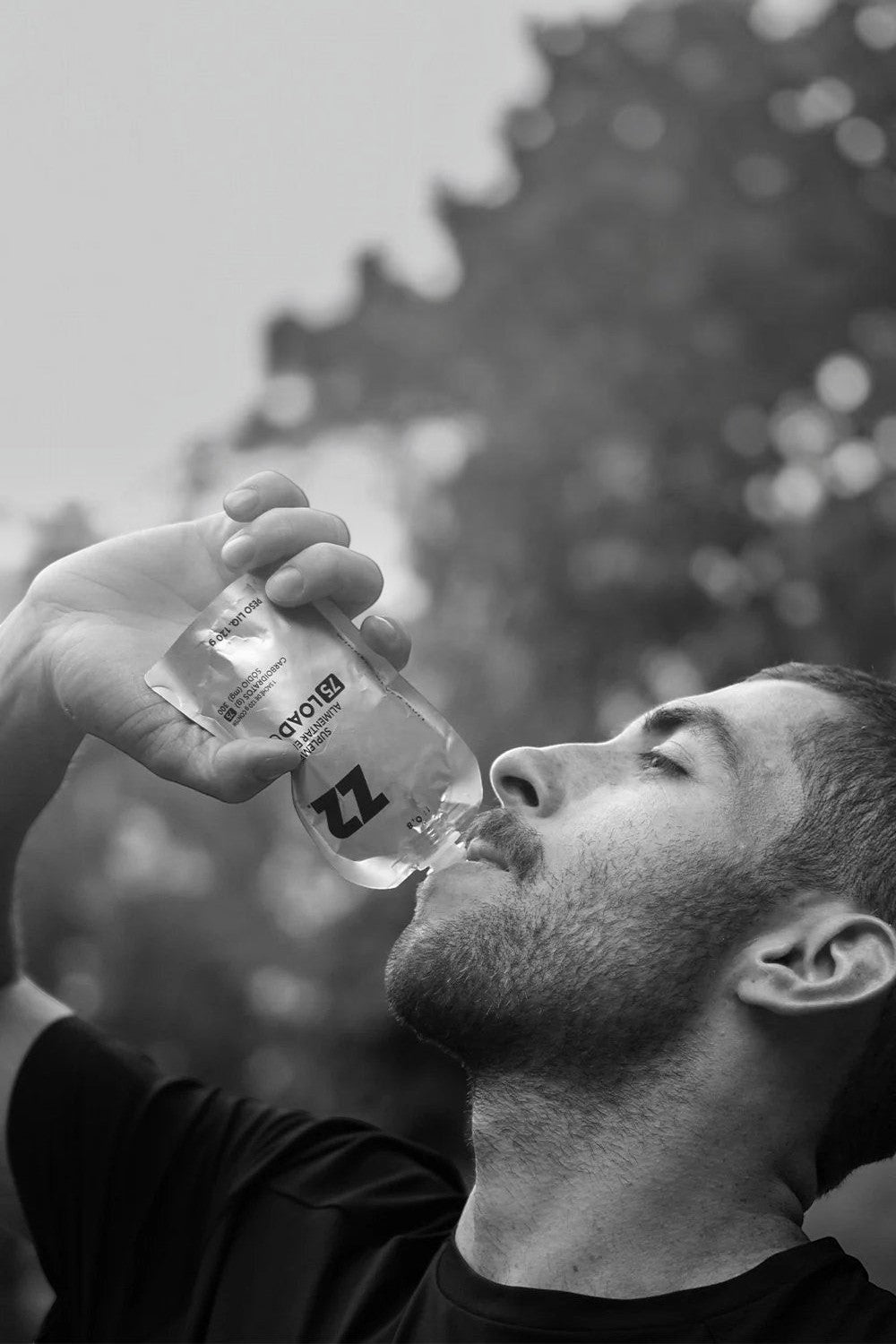 Atleta SPORTBR consumindo sachê de gel de carboidrato Z2 LoadUp 75g com bico flask durante treino ao ar livre