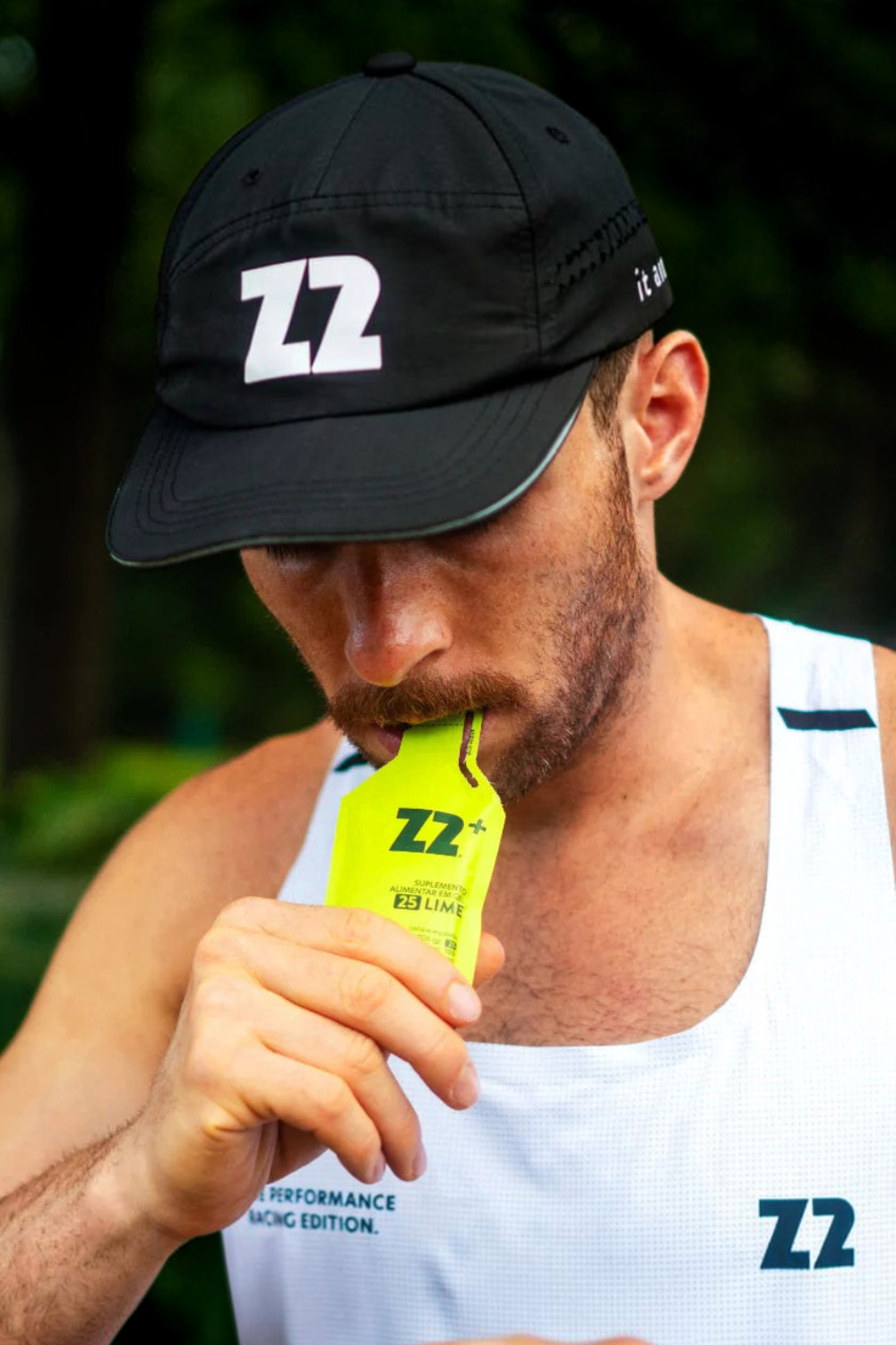 Atleta consumindo sachê de gel de carboidrato Z2+ sabor limão durante treino ao ar livre.