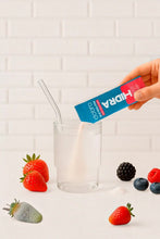 Sachê de eletrólitos em pó SPORTBR Dobro sabor frutas vermelhas sendo despejado em um copo com água
