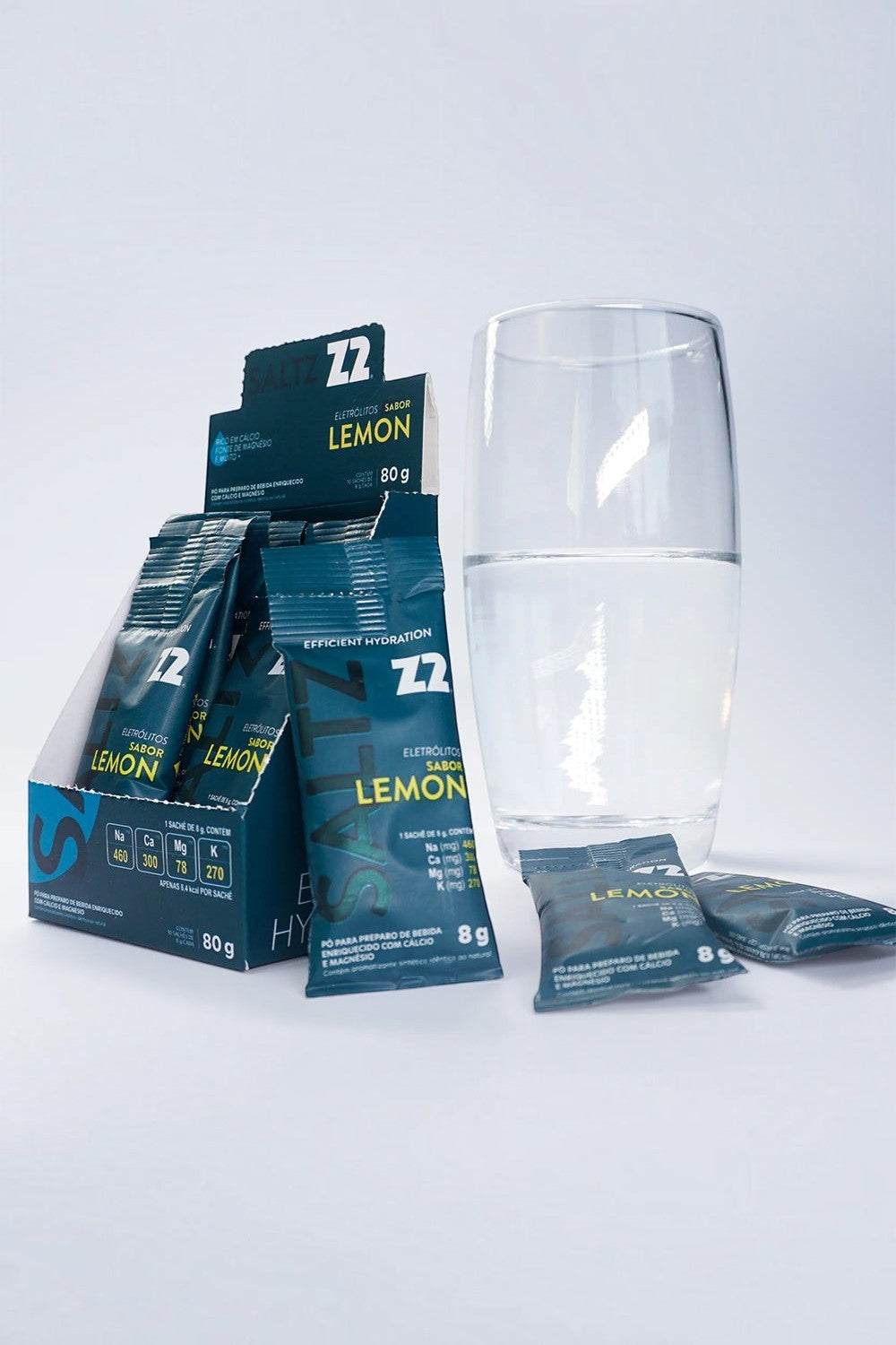 Sachê de eletrólitos SPORTBR Saltz Z2 sabor Lemon em pó ao lado de um copo com água para hidratação esportiva.