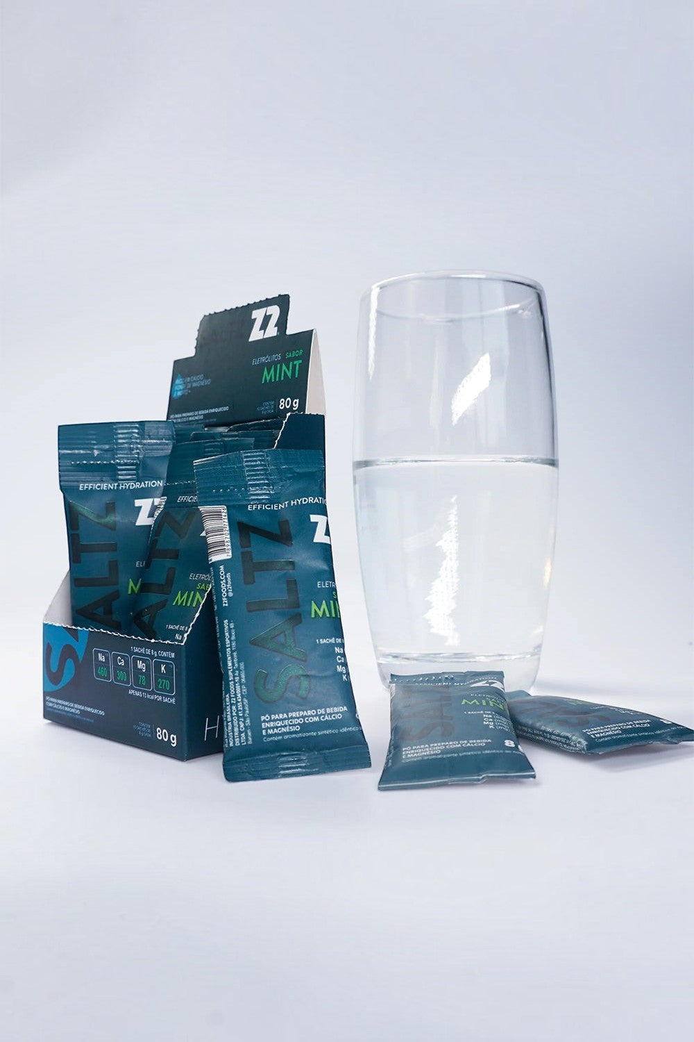 Sachê de eletrólitos em pó SPORTBR Saltz Z2 sabor Mint ao lado de um copo com água para hidratação esportiva