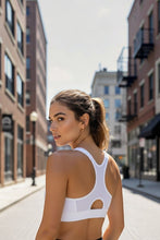 Modelo vestindo top branco de alta sustentação SPORTBR com alça nadador em rua urbana.