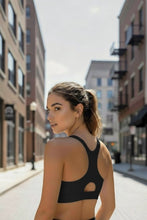 Mulher vestindo top esportivo preto de alta sustentação SPORTBR com alça nadador em ambiente urbano.