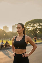 Mulher usando top esportivo preto de alta sustentação SPORTBR com modelagem nadador em parque ao ar livre.