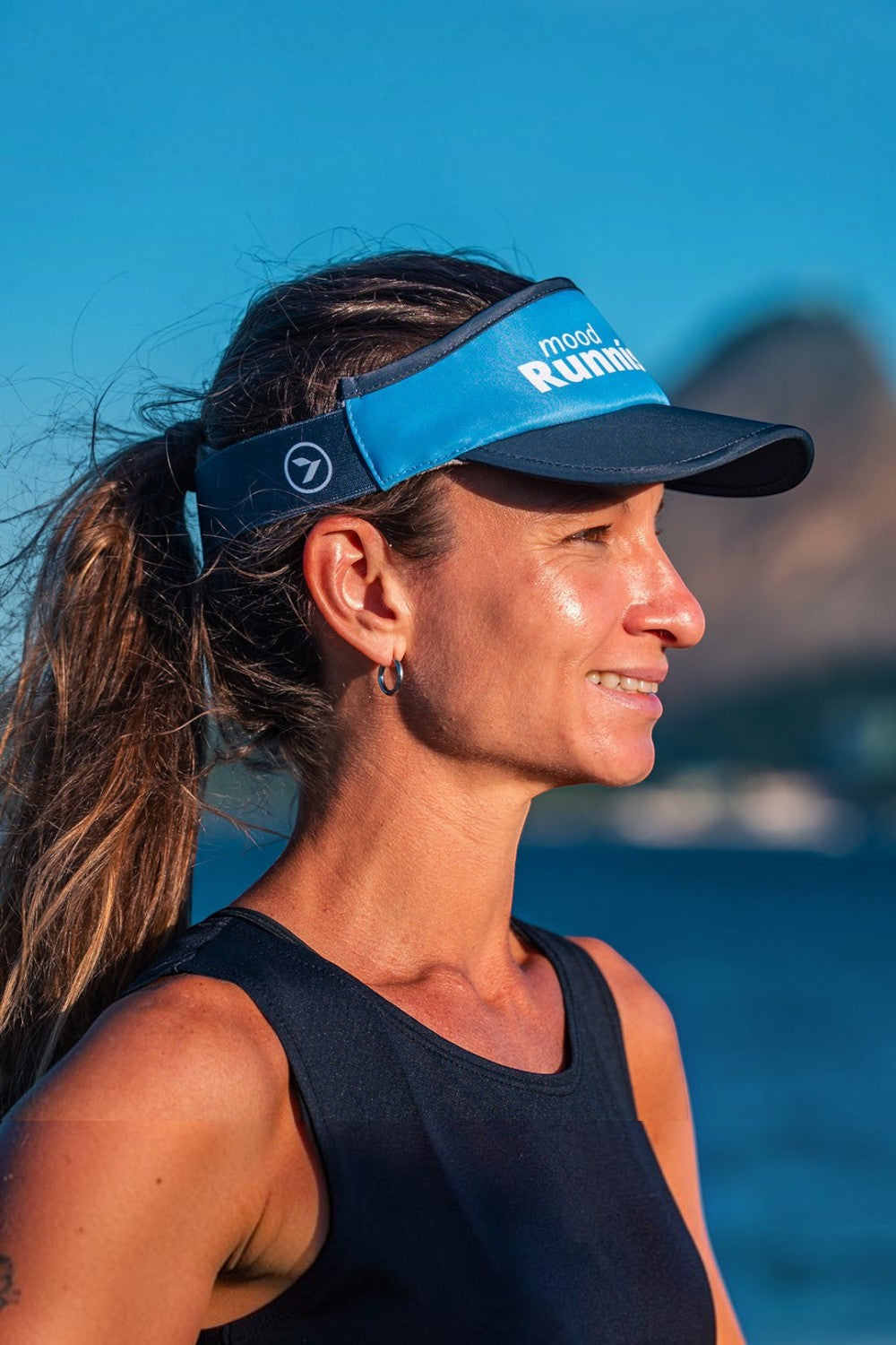 Mulher usando viseira de corrida azul SPORTBR com ajuste elástico e forro dry em ambiente externo ensolarado