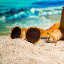 Óculos de sol caramelo unissex com armação redonda e lente marrom não refletiva, polarizada com proteção UV400. O acessório é leve, confortável e não escorrega ou pula no rosto ao realizar esportes.