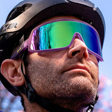 Óculos de sol roxo unissex com armação máscara e lente única verde espelhada, polarizada com proteção UV400. O acessório é leve, confortável e não escorrega ou pula no rosto ao realizar esportes.
