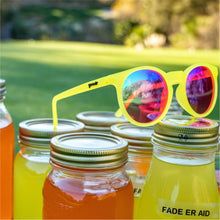 Óculos de sol amarelo unissex com armação redonda e lente rosa não refletiva, polarizada com proteção UV400. O acessório é leve, confortável e não escorrega ou pula no rosto ao realizar esportes.