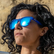 Óculos de sol azul unissex com armação quadrada e lente azul espelhada, polarizada com proteção UV400. O acessório é leve, confortável e não escorrega ou pula no rosto ao realizar esportes.